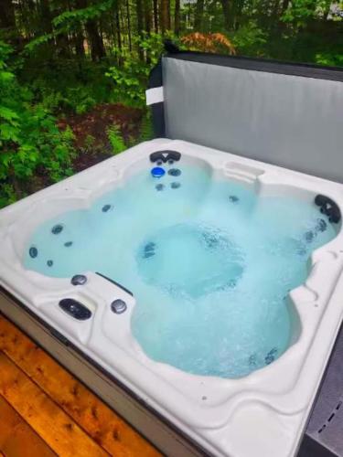 a white bath tub with blue water in it at Cozy Log Cabin with Spa - 3 min of Tremblant in Lac-Superieur
