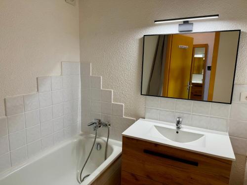 une salle de bain avec un lavabo, une baignoire et un miroir dans l'établissement Le Chalet de Bisanne, aux Saisies