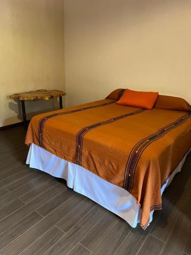 a bedroom with a large bed with an orange blanket at NEIZAN HOTEL in Antigua Guatemala