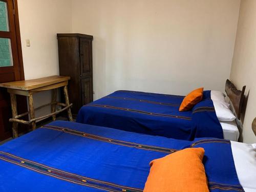 a room with two beds with blue sheets and a table at NEIZAN HOTEL in Antigua Guatemala