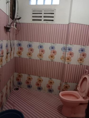 a bathroom with a pink toilet and flowers on the wall at Rimadi Lake Guest Inn in Eravur