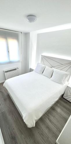 a white bedroom with a large bed with white sheets and pillows at APARTAMENTO LUXURY in Madrid