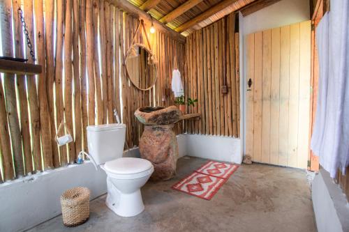 a bathroom with a toilet in a wooden wall at Cabana Serena in Corumbau