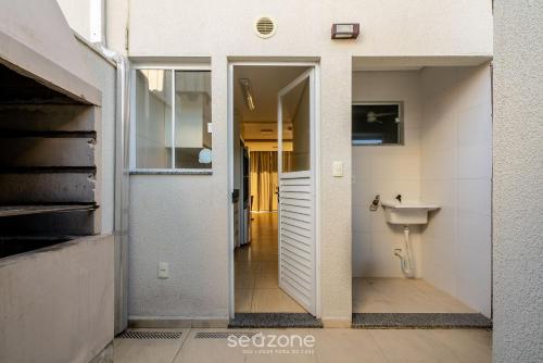 ein Bad mit einer Tür, die zu einem Waschbecken führt in der Unterkunft Casa 2Q c/ churrasq. 600m da praia RVL1183 in Canto Grande