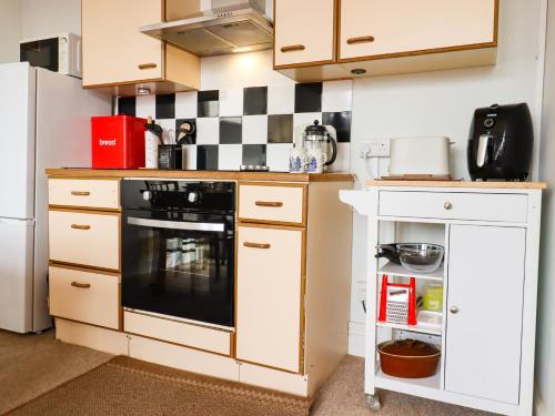 a small kitchen with a black and white tile wall at Sylvian in Bexhill