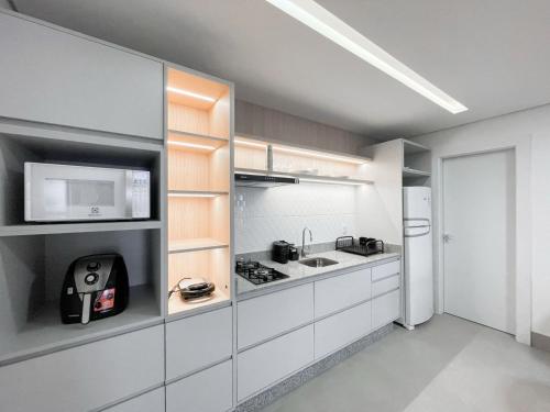 a kitchen with white cabinets and a microwave at Lindo Flat Planejado com Vista Para Cidade in Campo Grande