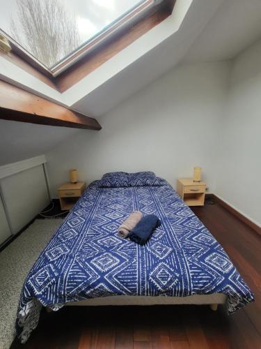 una camera da letto con un letto con un piumone blu e una finestra di GRAND DUPLEX proche de PARIS a Saint-Maur-des-Fossés