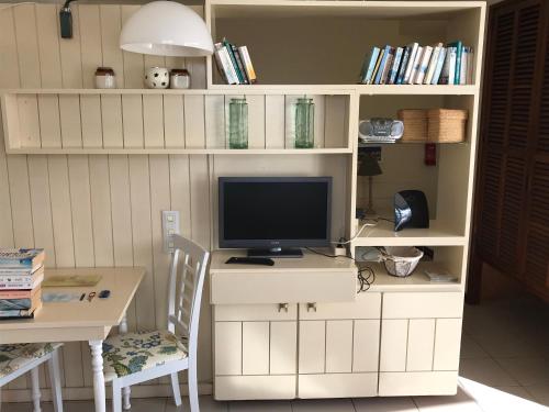 a computer desk with a tv on a white book shelf at Апартаменты 303 - Studio in Funchal