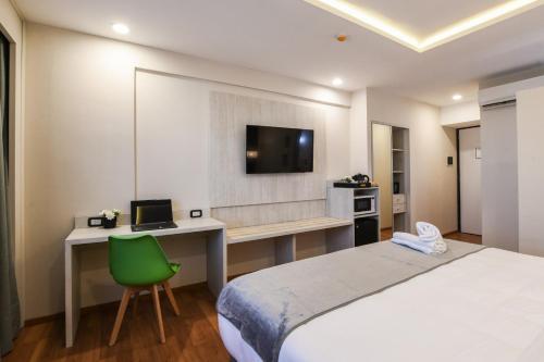a bedroom with a bed and a desk and a tv at Hotel Innovo in Rosario