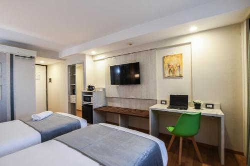 a hotel room with two beds and a desk with a laptop at Hotel Innovo in Rosario