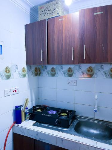 a kitchen with a stove and wooden cabinets at Imastay in Mombasa