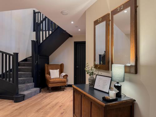 a living room with a staircase and a table with a lamp at Converted Welsh Sunday School with Sea View & Garden on Anglesey - Dog Friendly in Amlwch