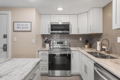 a kitchen with white cabinets and a stove top oven at On Famous Music Row - Pool, Parking, Walk to Bars in Nashville