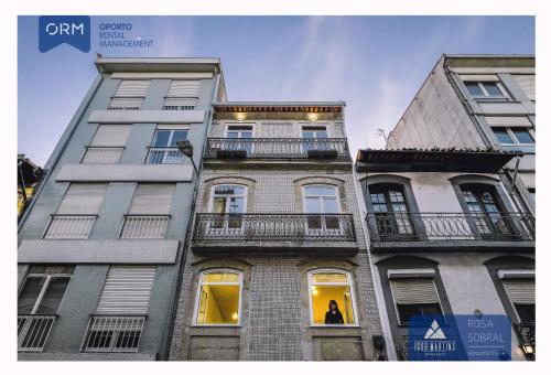 a tall building with balconies and a person in the window at ORM - Almada Apartments in Porto