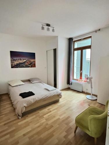 une chambre avec un lit, une chaise et une fenêtre dans l'établissement Des appartements au calme dans un immeuble historique, à Béziers