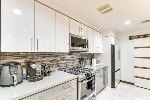 a kitchen with white cabinets and a stove top oven at Modern Oasis with Outdoor Lounge in Houston! in Houston