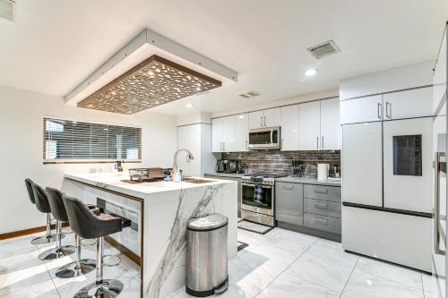 a kitchen with white cabinets and a island with bar stools at Modern Oasis with Outdoor Lounge in Houston! in Houston