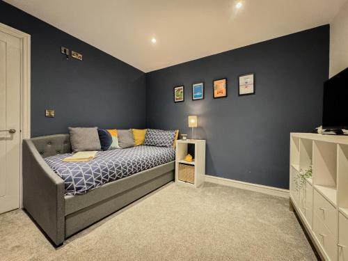 a bedroom with a bed and a blue wall at Converted Welsh Sunday School with Sea View & Garden on Anglesey - Dog Friendly in Amlwch