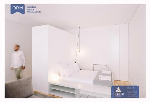 a man standing in a white room with a bed at ORM - Almada Apartments in Porto