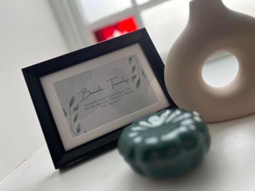 a picture frame next to a vase and a cookie at Converted Welsh Sunday School with Sea View & Garden on Anglesey - Dog Friendly in Amlwch