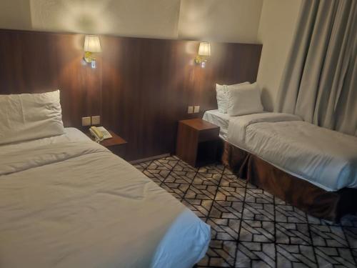 a hotel room with two beds and two lamps at فندق مواسم العزيزية in Al ‘Azīzīyah