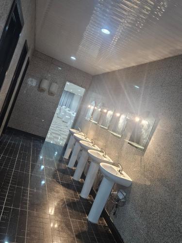 a bathroom with a row of sinks and mirrors at فندق مواسم العزيزية in Al ‘Azīzīyah