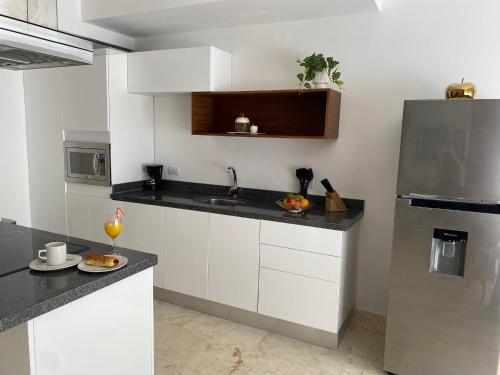 a kitchen with white cabinets and a stainless steel refrigerator at Anah Village in Akumal