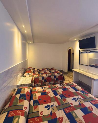a hotel room with two beds and a tv at Hotel Arboledas Industrial in Guadalajara