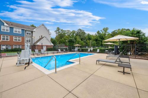a swimming pool with two chairs and an umbrella at Sonesta ES Suites Raleigh Cary in Cary