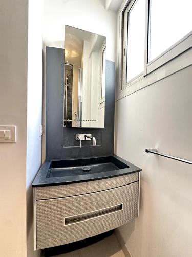 une salle de bain avec un lavabo noir et un miroir dans l'établissement 2 bedrooms with see view, à Cannes