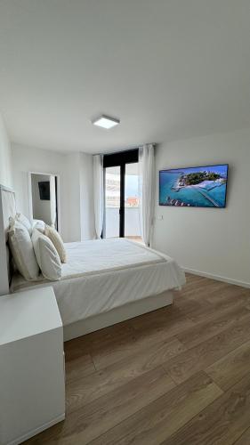 ein weißes Schlafzimmer mit einem großen Bett und einem großen Fenster in der Unterkunft Apartamento Luxury in Valencia