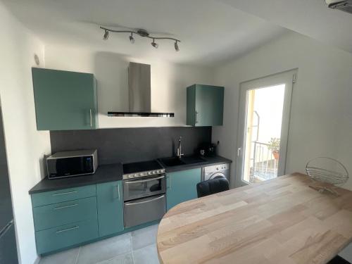 une cuisine avec des placards bleus et une table en bois dans l'établissement appartement les étoiles, à Antibes