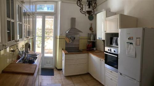une cuisine avec des armoires blanches et un réfrigérateur blanc dans l'établissement Spacieux Appartement indépendant, à Cannes