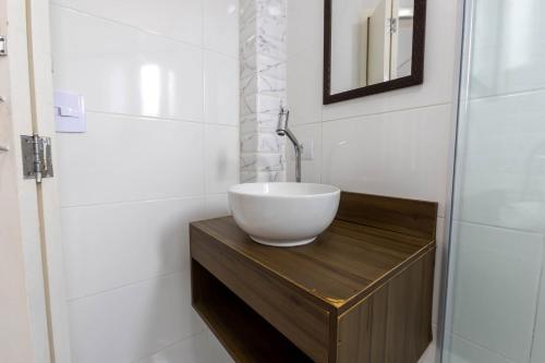 a bathroom with a bowl sink on a wooden table at Cobertura a beira mar com piscina e churrasqueira in Praia Grande