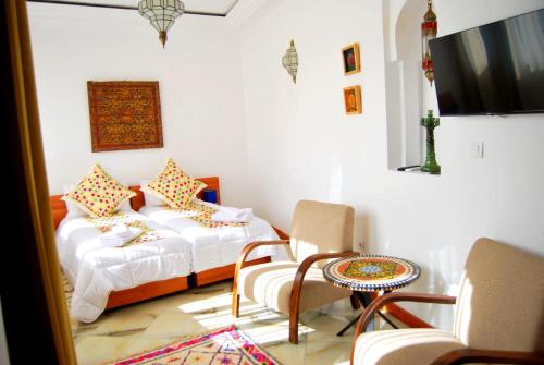 1 Schlafzimmer mit 2 Betten, einem Tisch und Stühlen in der Unterkunft Dar terrae plus in Chefchaouen