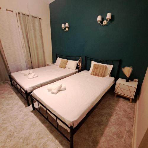 two beds in a room with green walls at Central Piraeus port apartment in Piraeus