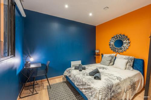 - une chambre bleue et orange avec un lit et un bureau dans l'établissement La tavernne de Balaach Clim Wifi Cozy, à Carcassonne