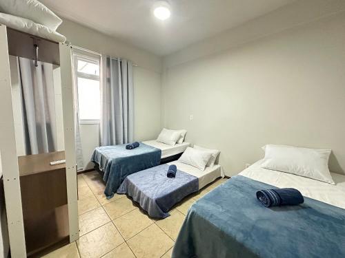 a room with two beds and a window at Ap a alguns passos da praia do Bosque | ROGR207 in Rio das Ostras