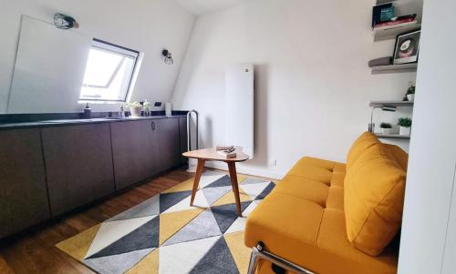 un salon avec un canapé jaune et une table dans l'établissement Charming Aligre Bastille Neighborhood Studio, à Paris