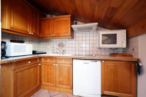 - une cuisine avec des placards en bois et des appareils blancs dans l'établissement Résidence Les Hauts De Chavants - Hauts de Chavants Albert 1er 13 MAE-6404, aux Houches