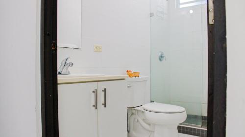 a white bathroom with a toilet and a sink at Arecibo Hotel 2104 in Arecibo