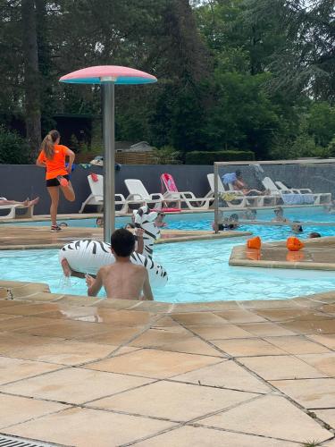 un homme assis dans une piscine avec un parasol dans l'établissement Mobile home 6 personnes 3 chambres tout confort, à Camiers