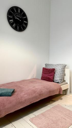 a black clock on a white wall above a bed at Beautiful Rooms - Wały Chrobrego in Szczecin