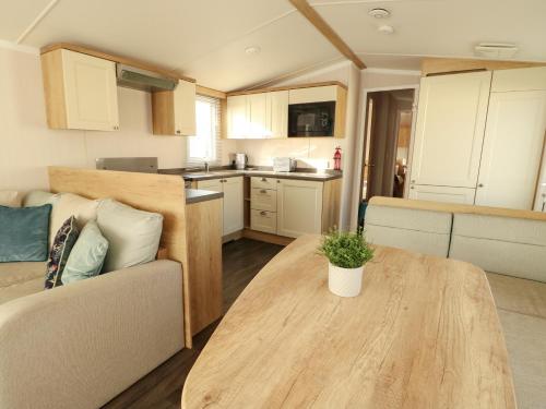 a kitchen and living room with a table and a couch at Blue Skies in Caernarfon