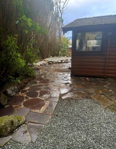 a stone walkway next to a house with a building at Misty Mountain Log Cabin - Trawsfynydd in Trawsfynydd