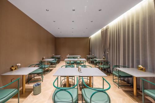 a dining room with tables and green chairs at G5 Shang Hotel - Kunming Railway Station Huan Cheng Nan Road Metro Station Branch in Kunming