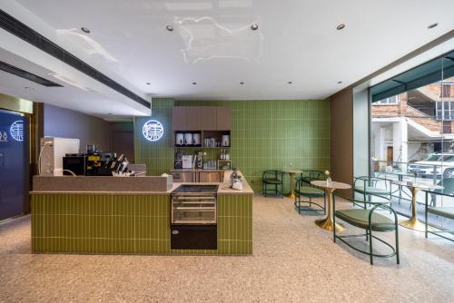 a restaurant with green walls and tables and chairs at G5 Shang Hotel - Kunming Railway Station Huan Cheng Nan Road Metro Station Branch in Kunming