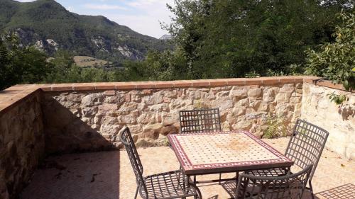a table and chairs on a patio with a stone wall at Borgo Pizzicarè in Vado