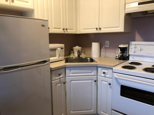 a kitchen with white cabinets and a sink at Super 8 by Wyndham Lake Country/Winfield Area in Winfield
