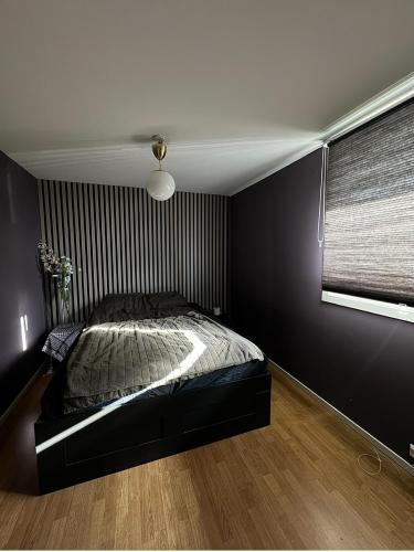 a black bedroom with a bed and a window at Koselig leilighet in Stavanger